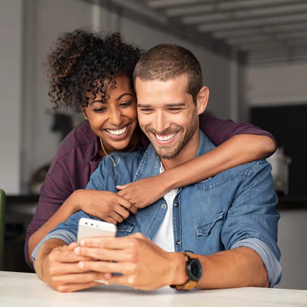 Couple smiling together while using a phone